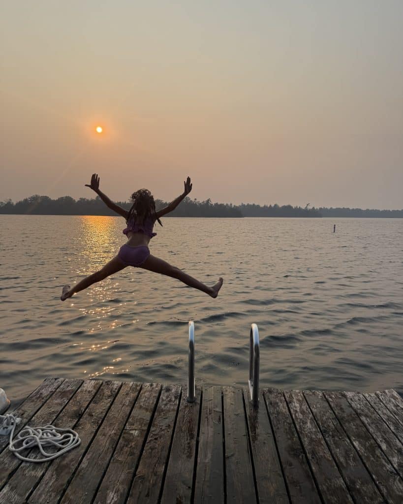 girl jumping into the lake at sunset.